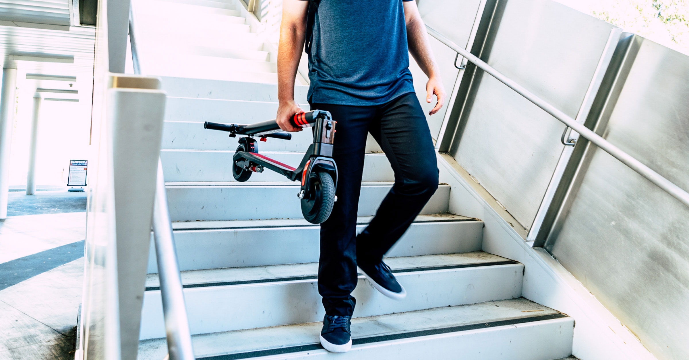 Folded electric scooter being walked down stairs