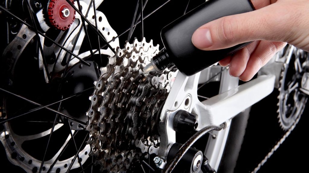 Closeup of someone oiling the chain of their electric bike.