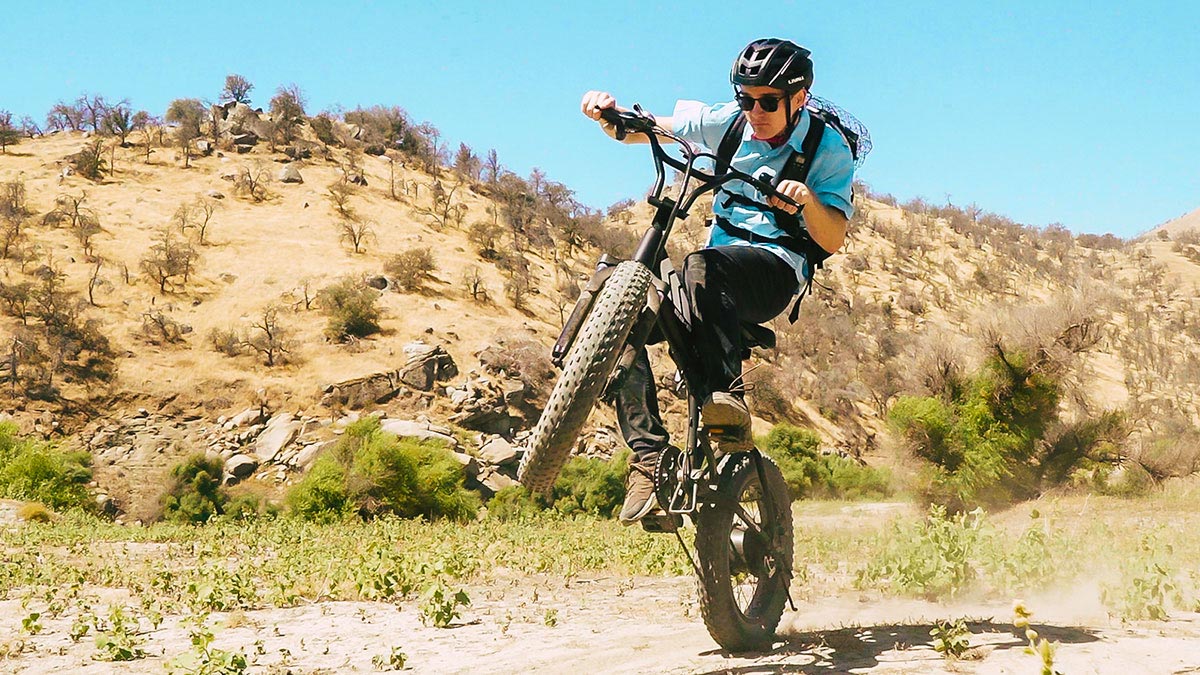 Close-up of man popping a wheelie while trail riding on an EB8 e-mtn bike.