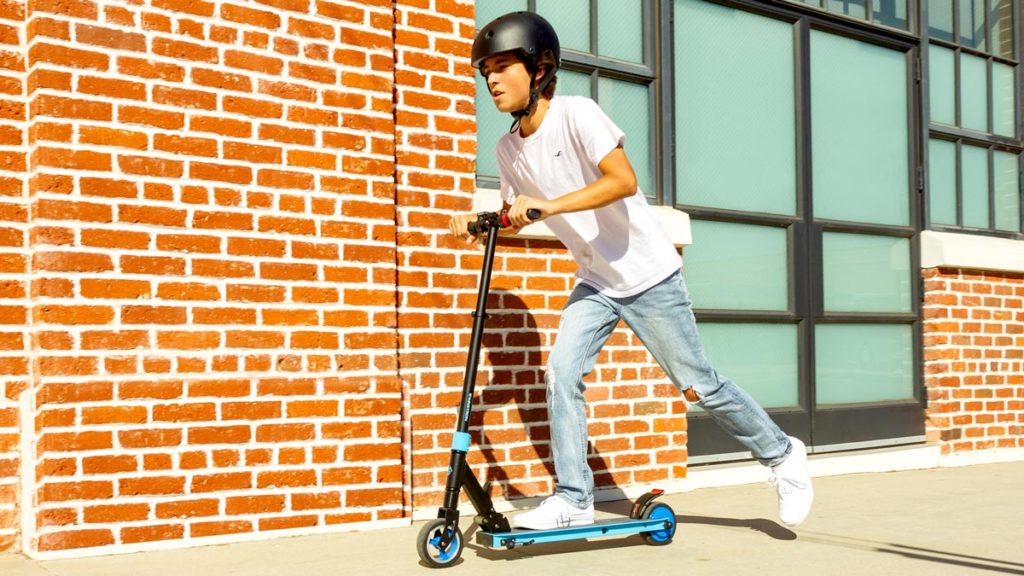 Kid wearing a helmet riding on a Swagger 8 electric scooter.