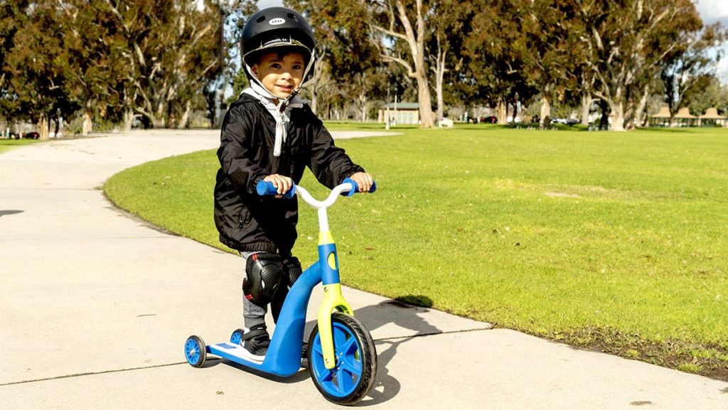 Young boy toddler wearing a helmet, riding on a K6 4-in-1 ride-on scooter.