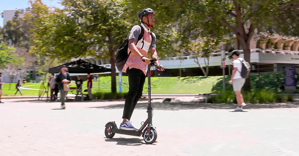 College guy riding on his Swagger 5 eScooter, wearing a helmet to prevent head injuries