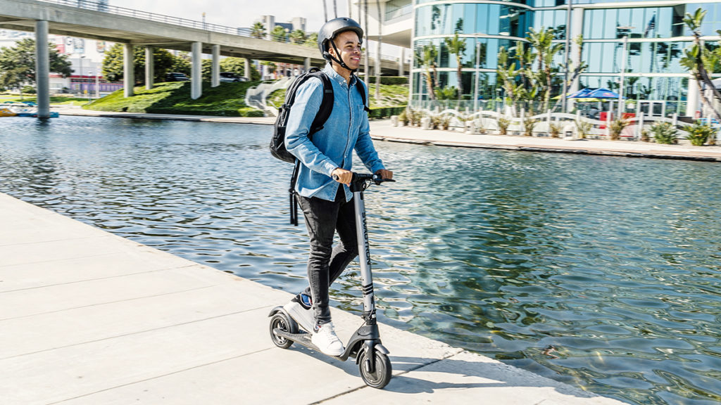 Man wearing helmet riding the Swagger 7 electric scooter.