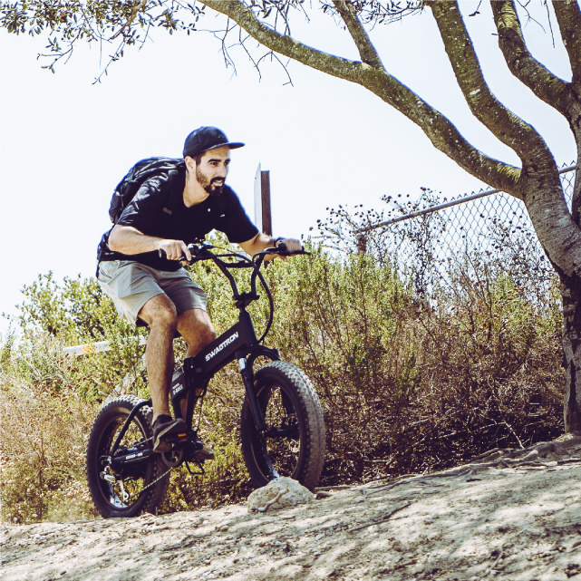 Man climb hills with the Electric Fat Tire All-Terrain Bike; ideal for off roads and trails