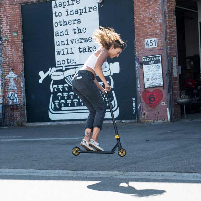 Woman in skater shoes jumps on on stunt scooter