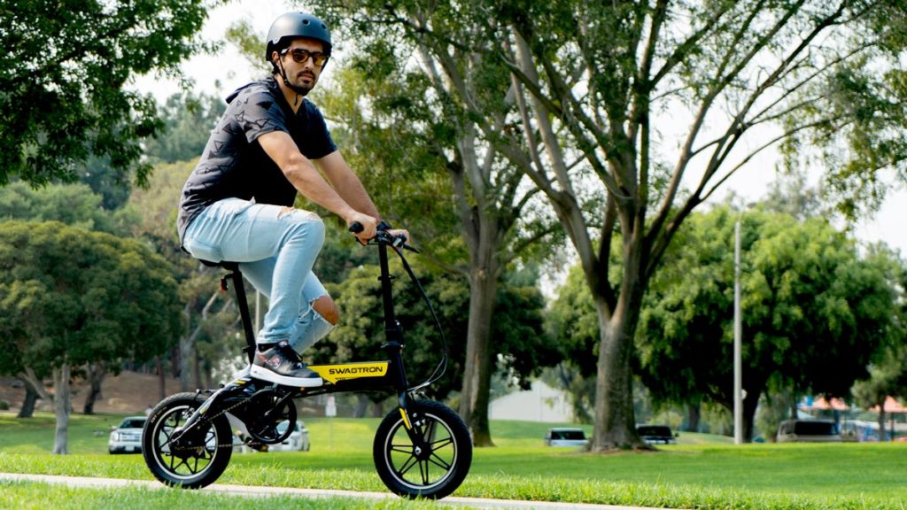 Guy wearing sunglasses and helmet riding an EB5 Pro Plus eBike in the park.