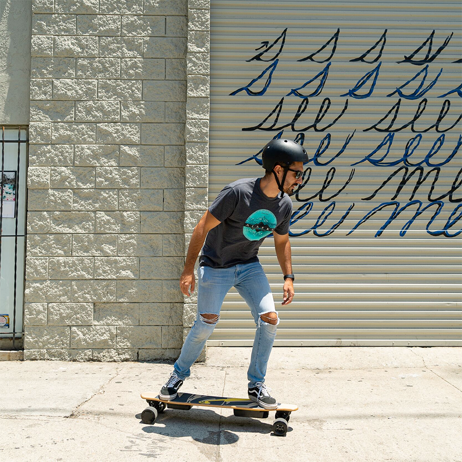 Young man riding his NG2 Electric Longboard powered by control remote